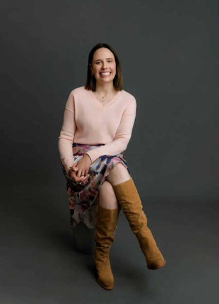 May contain person wearing pink sweater, floral skirt, and brown boots.