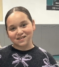May contain a person wearing a black sweater with purple bow patterns and black skirt.